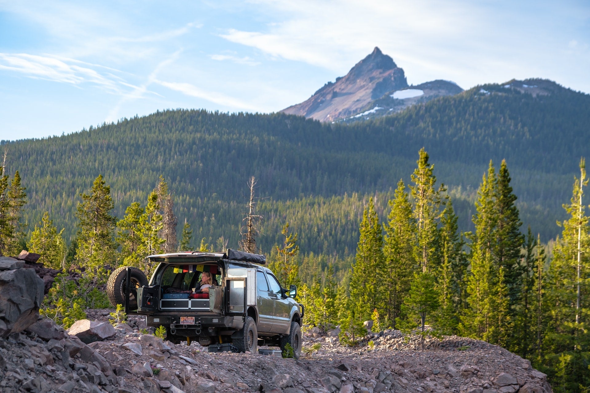 Image of a 4x4 vehicle parked in a camping area in a heavily wooded mountainous area