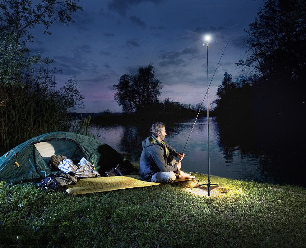 man shoreline fishing a lake at night sitting next to a tent scene illuminated by a FLi-Pro telescoping light