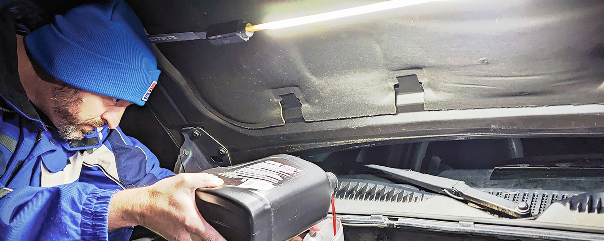 male adding fluids to his engine at night illuminated by a FLEXIT Under Hood Light.