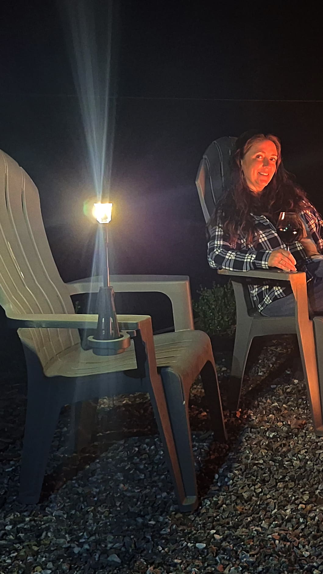 Person sitting outdoors at night with a flashlight illuminating the area.
