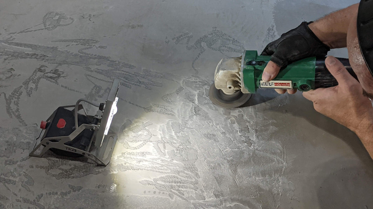 Person using a grinder on a concrete surface with a Mobile Task Light illuminating the area.